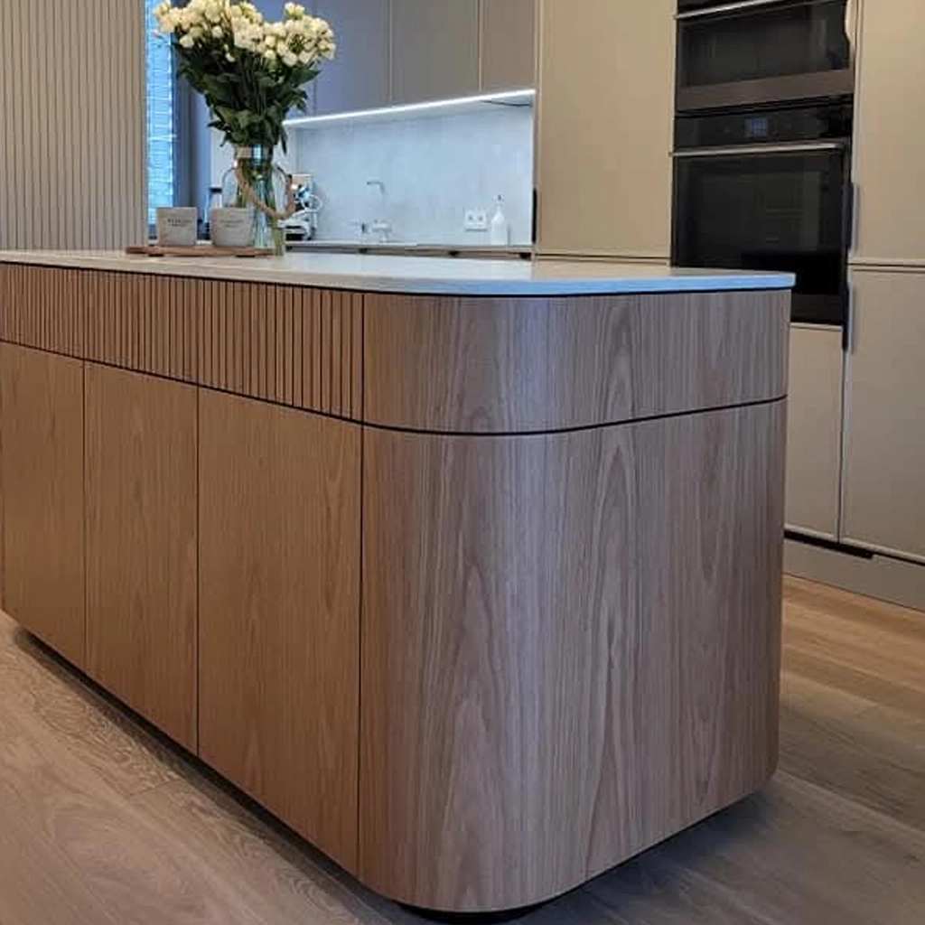 Kücheninsel nach Maß mit gerundeten Ecken, Fronten in Holzoptik mit Lamellendetail und heller Arbeitsplatte.